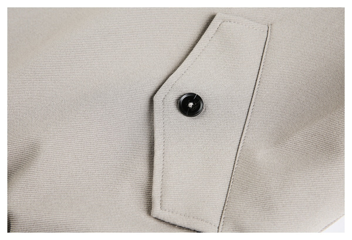 Close-up of a black button on a stitched gray jacket tab.