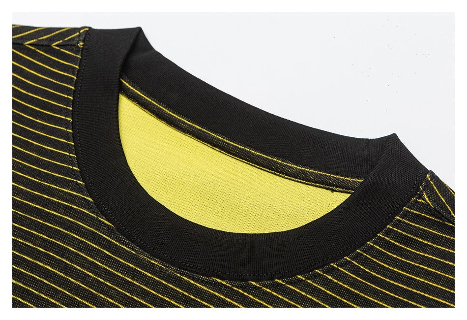 Close-up of a black ribbed crew neckline on black fabric with thin yellow stripes and a yellow inner panel.