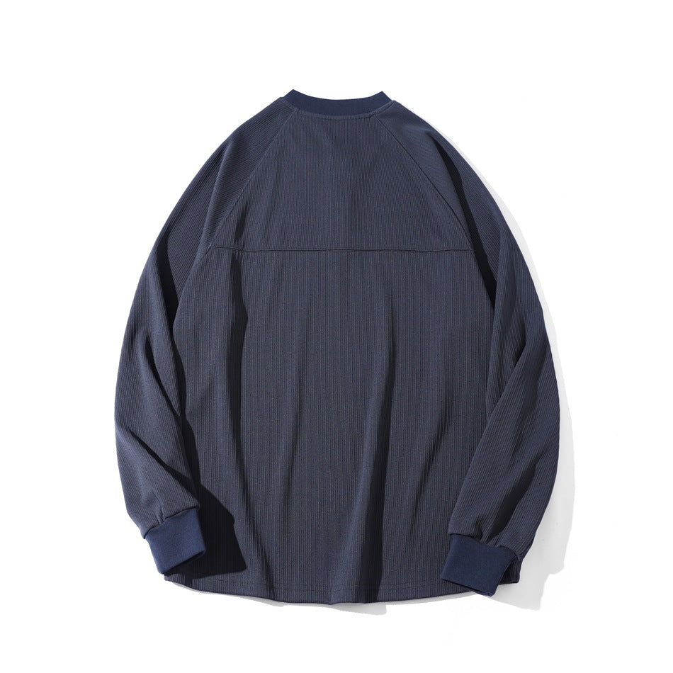 Back view of a navy ribbed long-sleeve top with raglan seams and ribbed cuffs, laid flat.