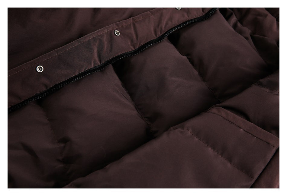Close-up of a dark burgundy padded coat showing a black zipper beneath a snap-fastened placket.
