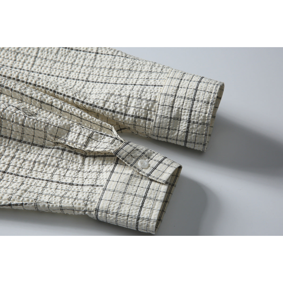 Close-up of the cream checked shirt's long sleeves and buttoned cuffs.