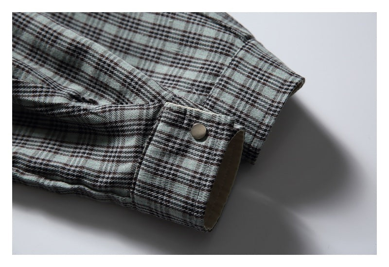 Close-up of a gray plaid sleeve cuff with a metal snap and beige inner lining.