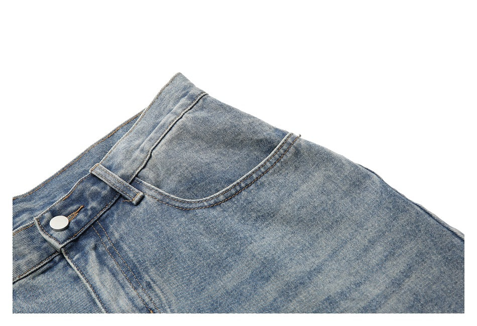 Close-up of a curved front pocket and button on light-wash blue jeans.
