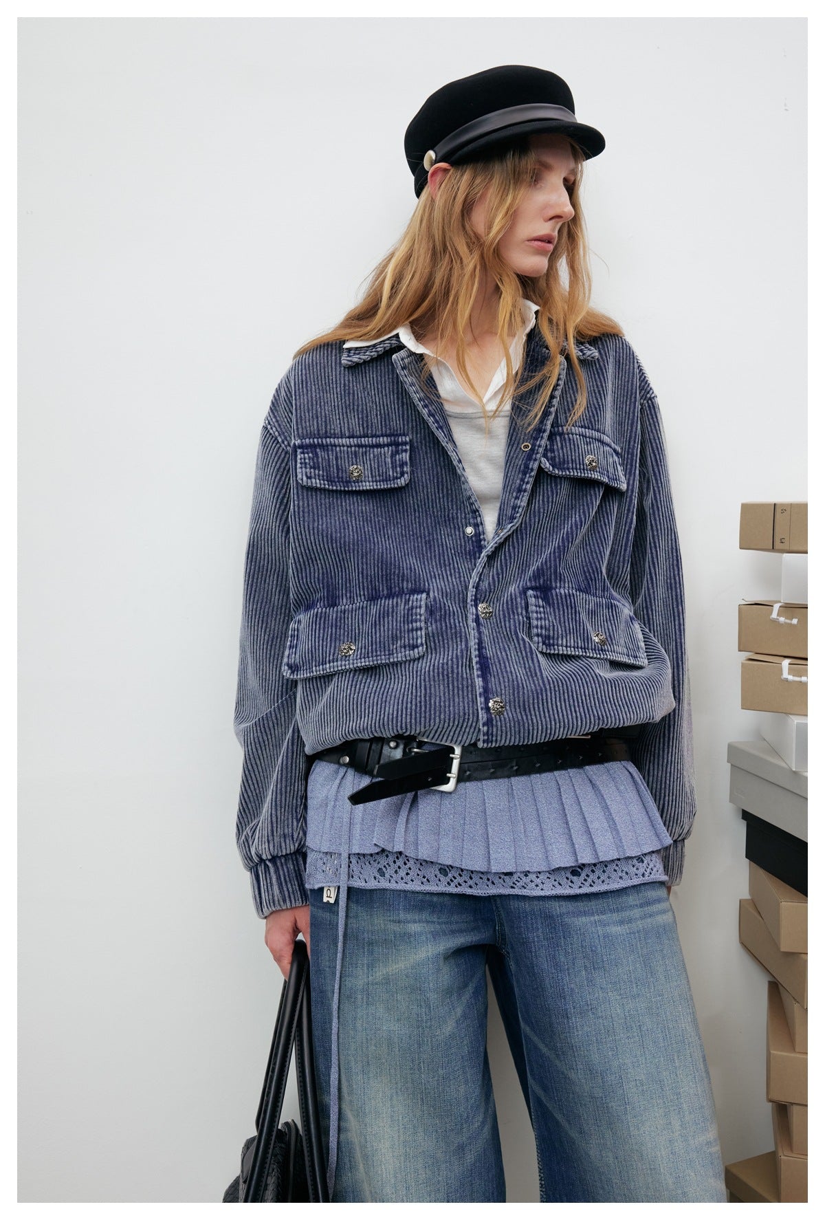 Model wearing a blue-gray ribbed jacket with four flap pockets, front buttons, and gathered cuffs and hem.