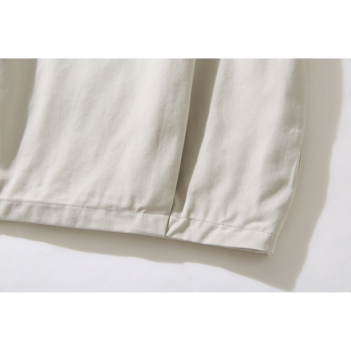 Close-up of the ivory jacket's lower hem and sleeve cuff with visible stitching.