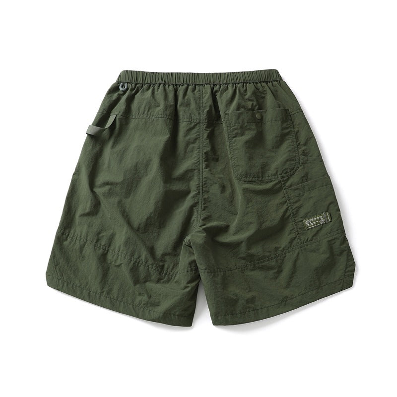 Dark olive shorts shown from the back, with an elastic waist, single patch pocket, side tab and small leg label.
