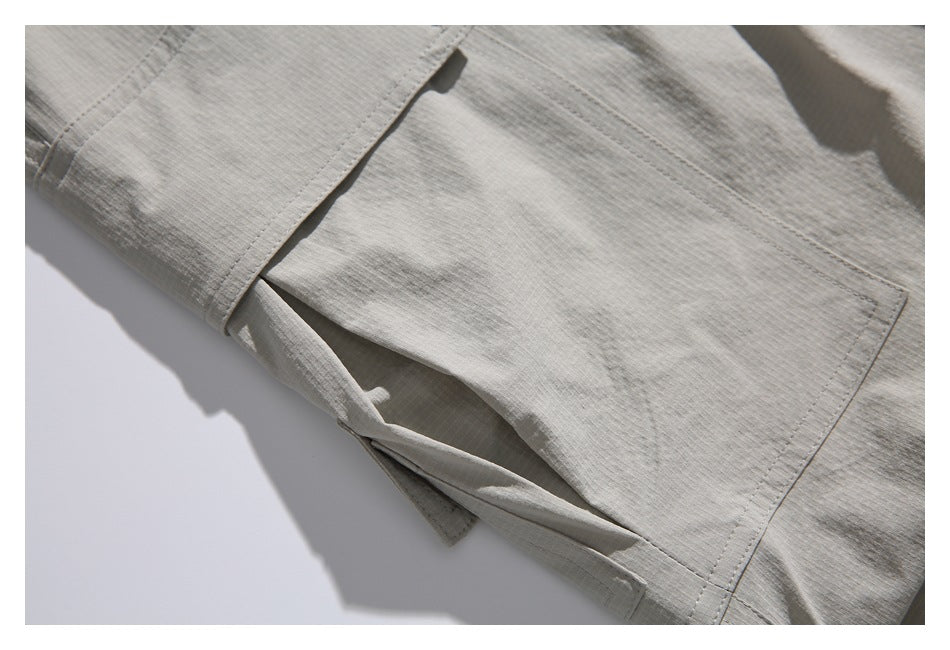 Close-up of a flap cargo pocket and stitching on light gray-beige trousers.