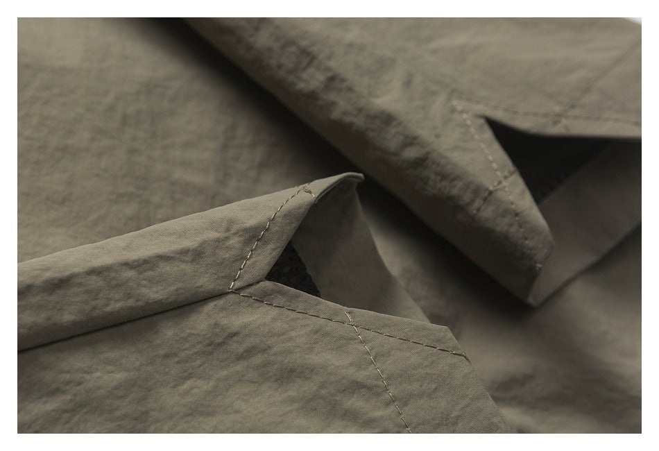 Close-up of taupe garment seams and folded edges with dark dotted mesh visible underneath.