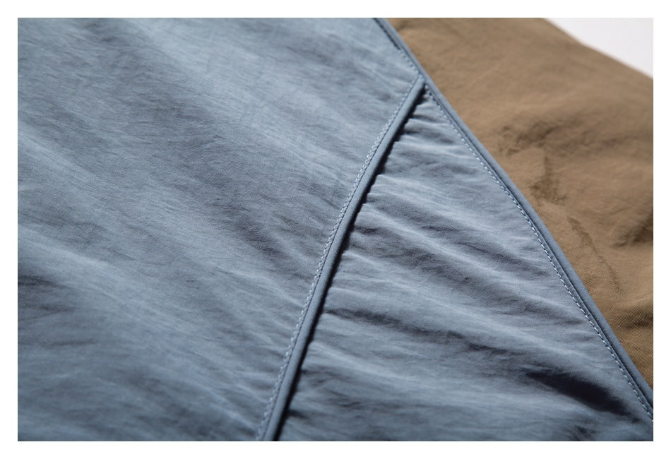 Close-up of slate-blue jacket fabric and stitched panel seams against brown fabric.