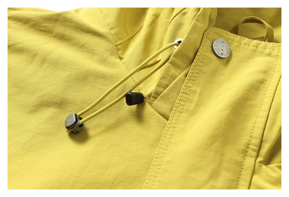 Close-up of the yellow jacket front showing an adjustable drawcord, toggles, metal snap, and stitched placket.