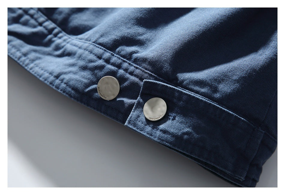 Close-up of a dark blue garment edge with two pale buttons and stitched detailing.