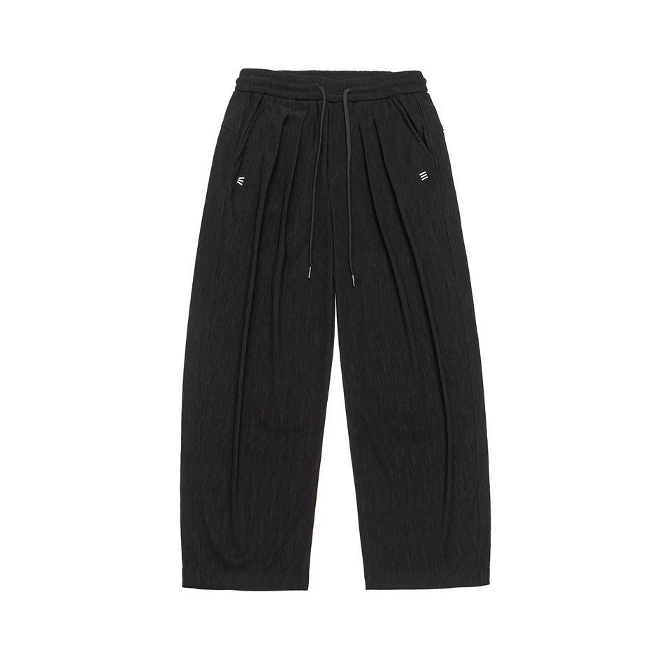 Black wide-leg drawstring pants with front pleats, side pockets and a textured fabric, flat lay front view