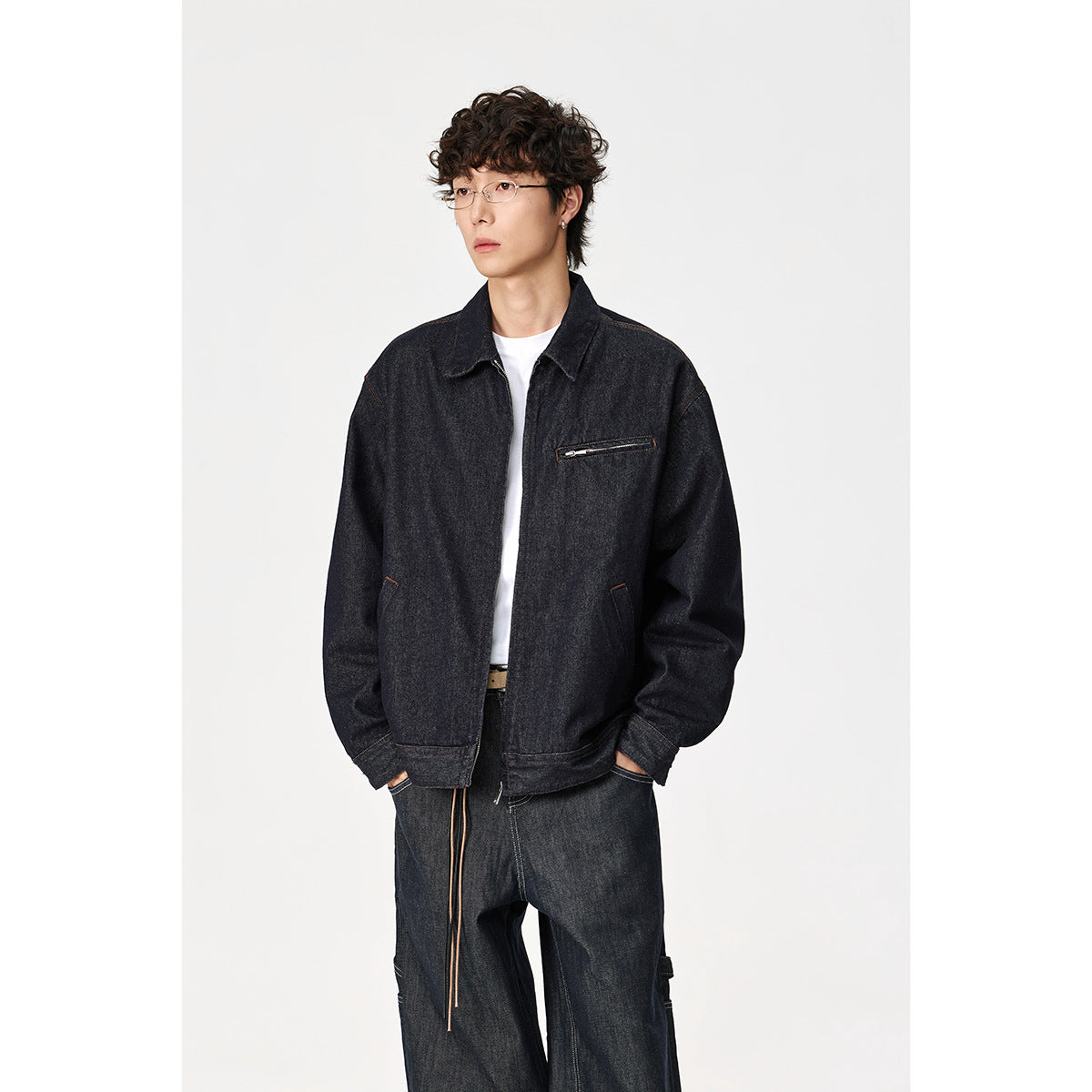 Model wearing a dark indigo denim jacket with a pointed collar, zip chest pocket and relaxed fit.