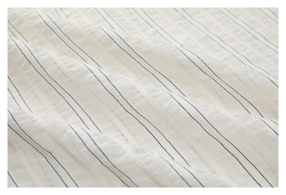 Close-up of off-white fabric with thin navy pinstripes and a subtle textured weave.