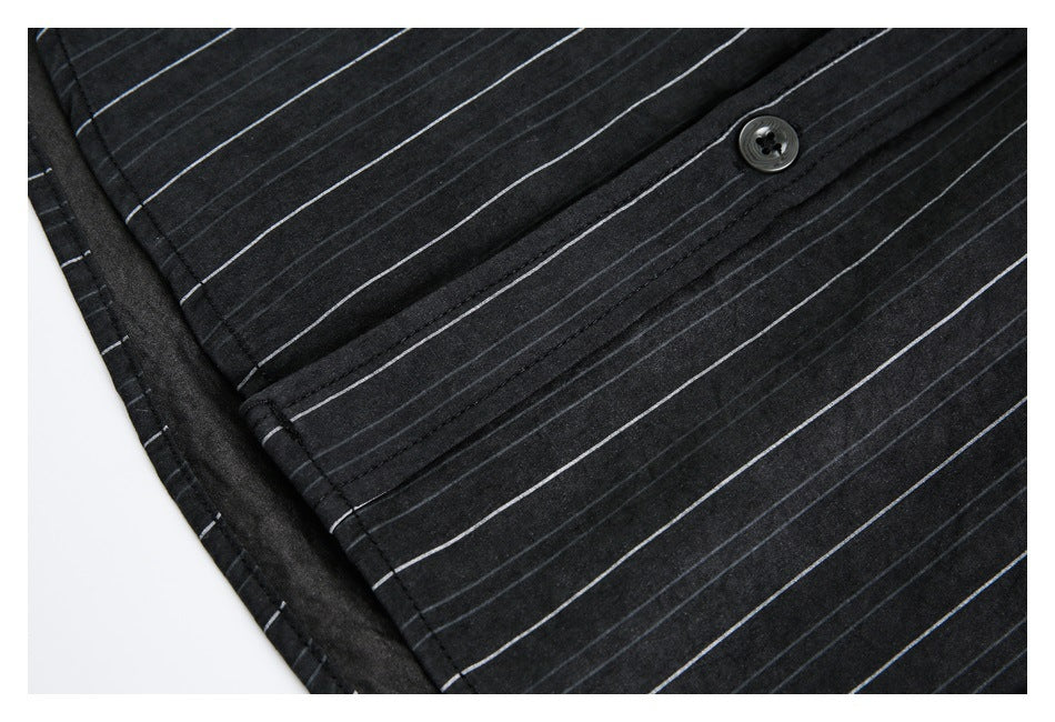 Close-up of a black pinstriped shirt showing a button, stitched placket, and side seam.