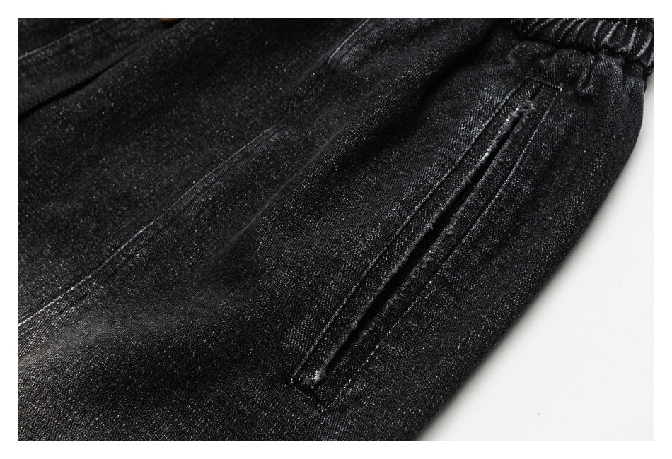 Close-up of a slanted pocket on black pants beside the gathered waistband.