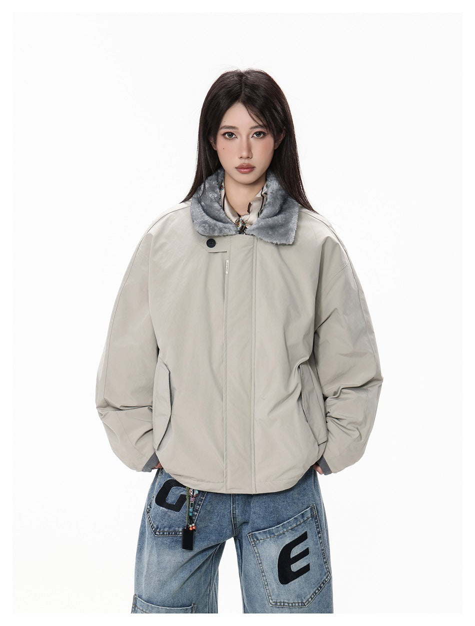 Front view of a model in a light gray oversized jacket with a gray plush collar and blue jeans with black letter patches.