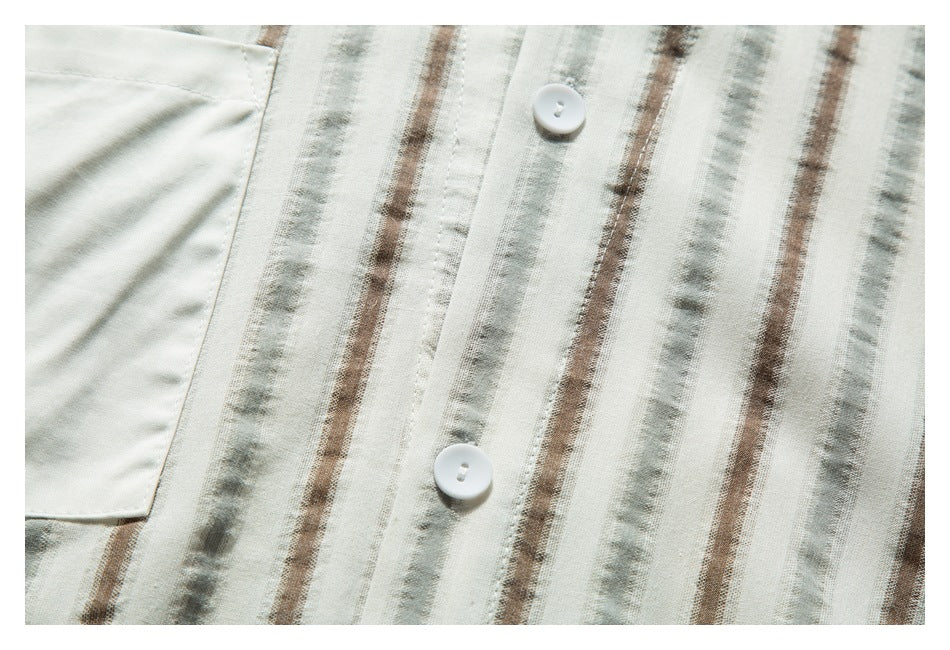 Close-up of two white buttons on the placket of a cream shirt with muted brown and gray vertical stripes.