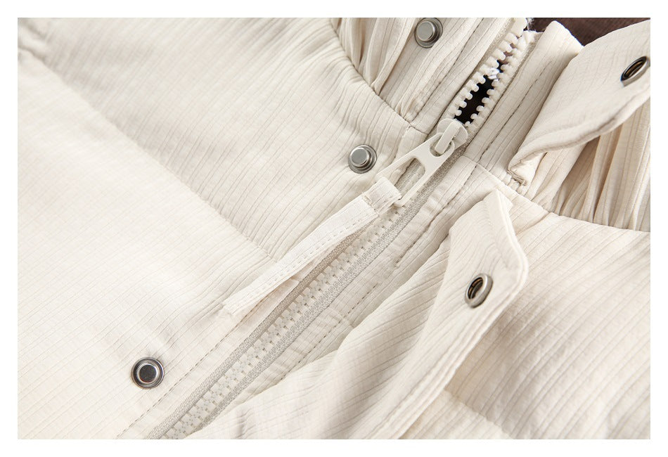 Close-up of an ivory jacket's front zipper, snap fasteners, and textured fabric.