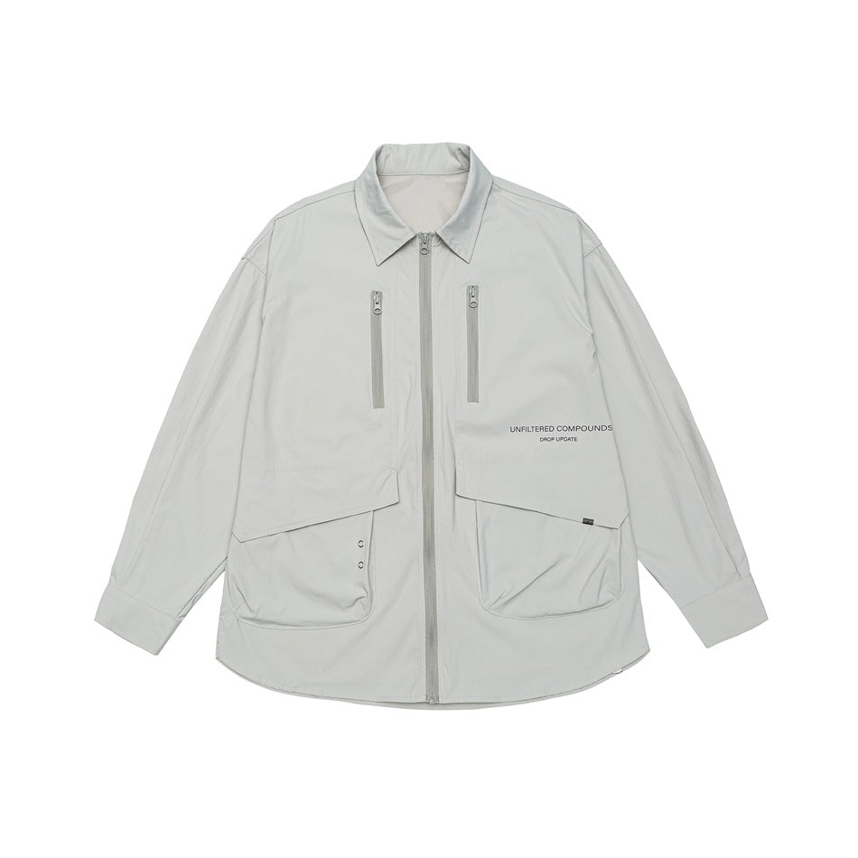 Light gray zip-front shirt-style jacket flat lay with chest zip pockets, large flap pockets and small chest print