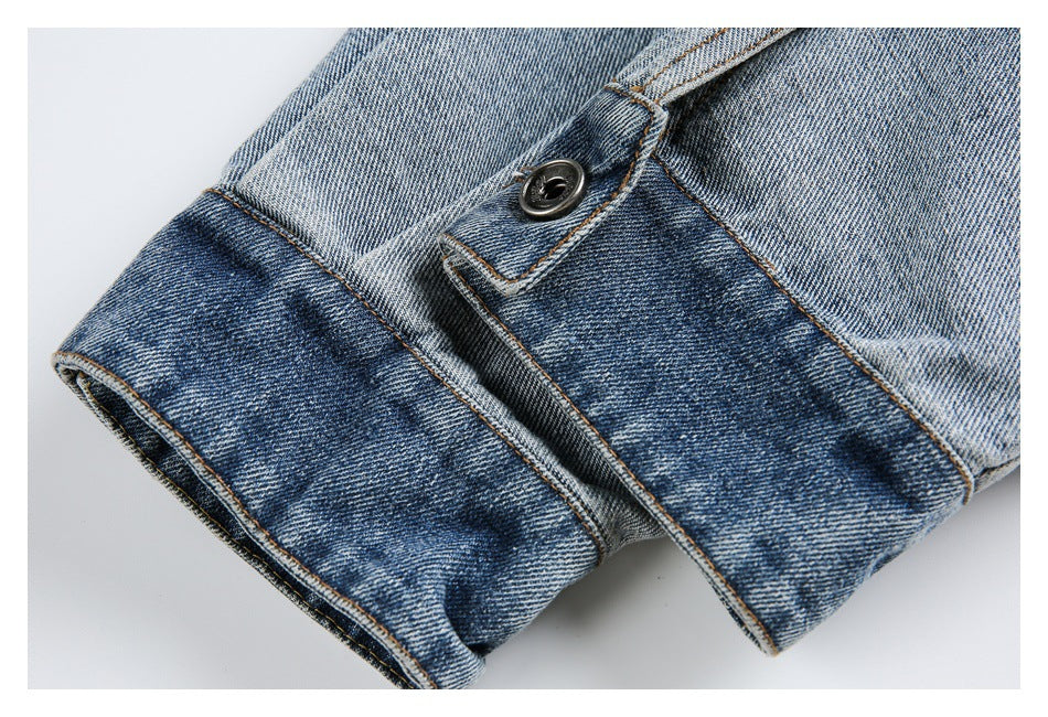 Close-up of a blue denim cuff with a dark button, folded edge and contrasting tan stitching.
