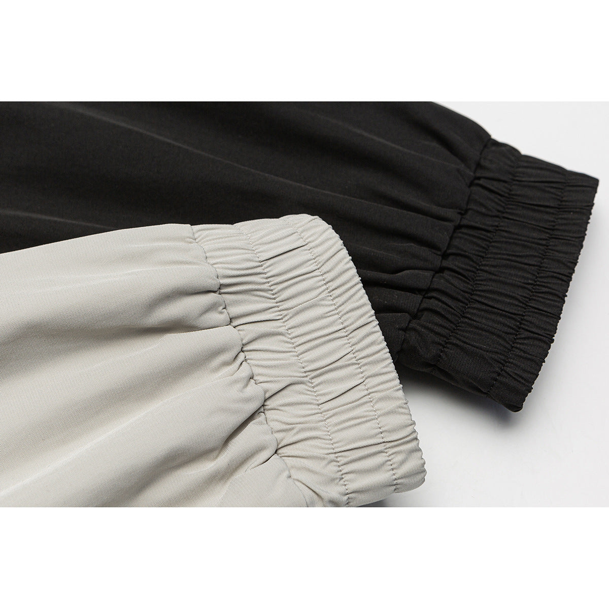 Close-up of gathered elastic cuffs on black and light gray jacket sleeves.