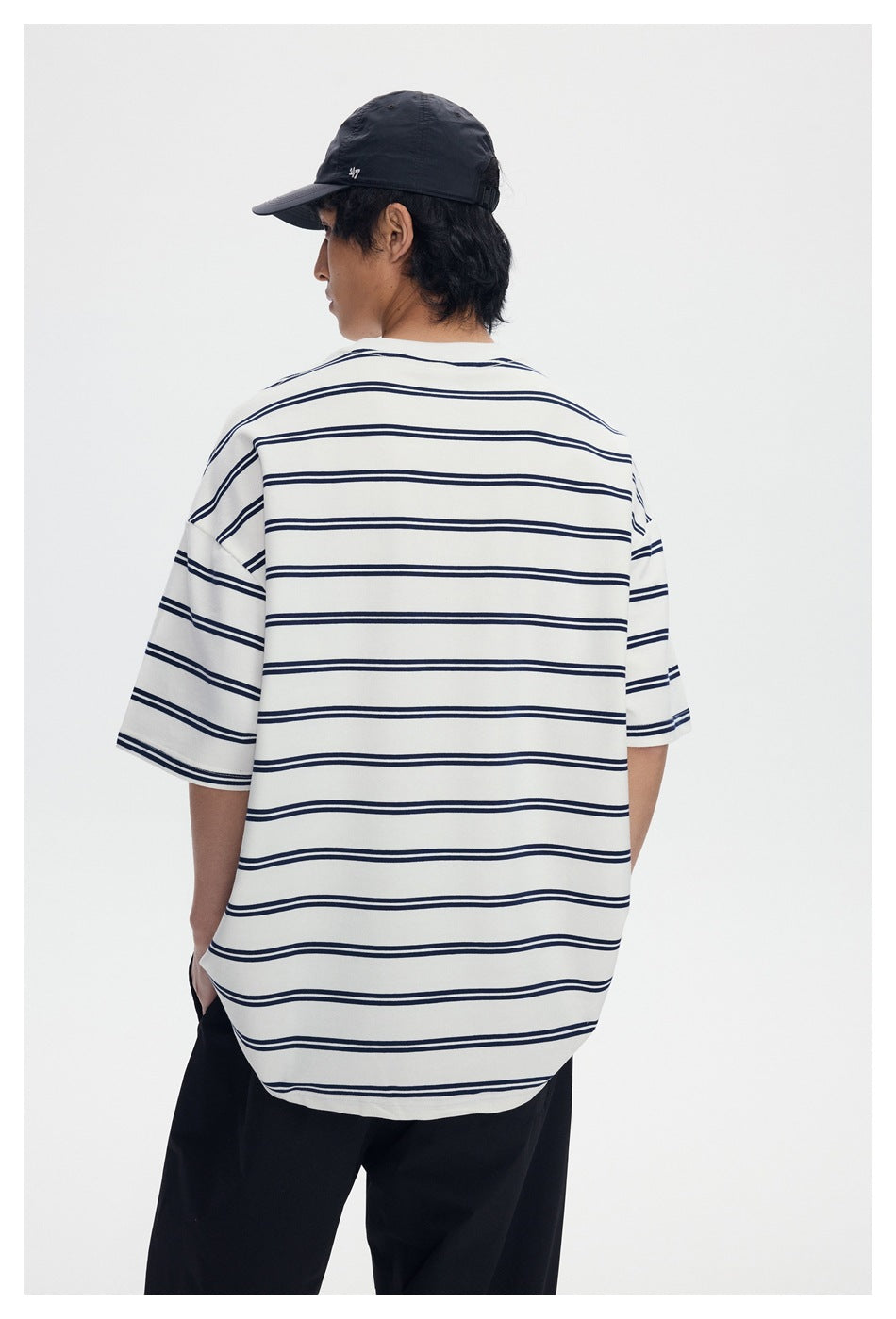 Back view of a model wearing an oversized white T-shirt with navy horizontal stripes.