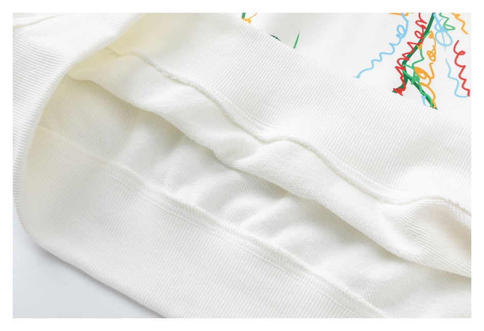 Close-up of the white sweatshirt's ribbed bottom hem and stitched seam, with part of the colorful print visible.