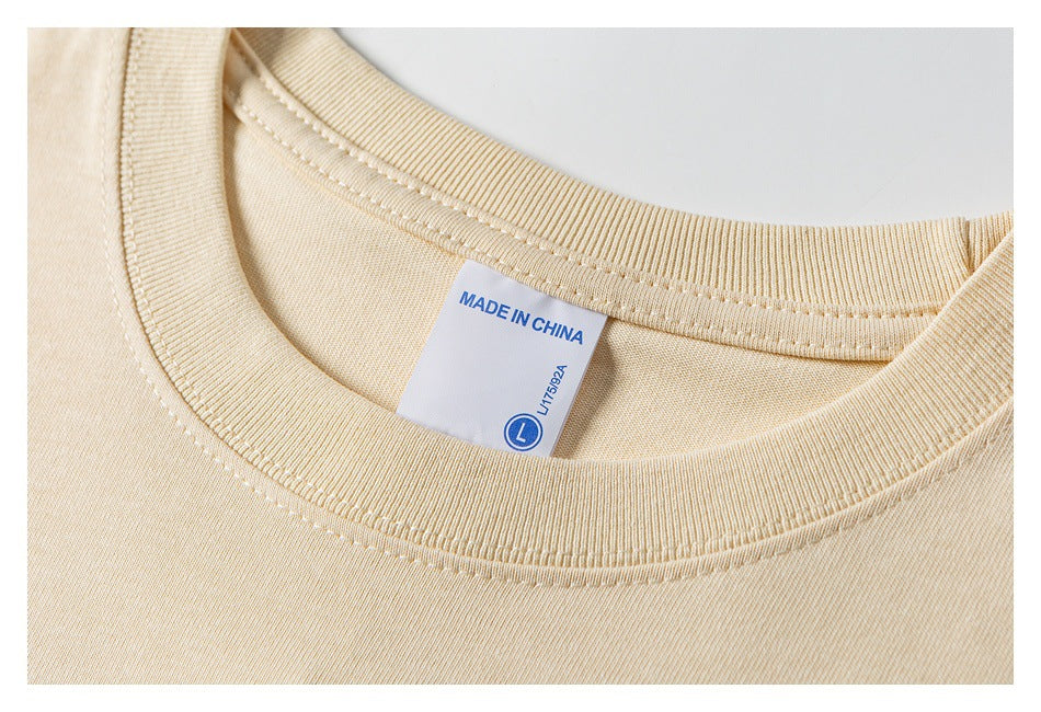 Close-up of the beige T-shirt’s ribbed crew neck and label marked MADE IN CHINA and size L.