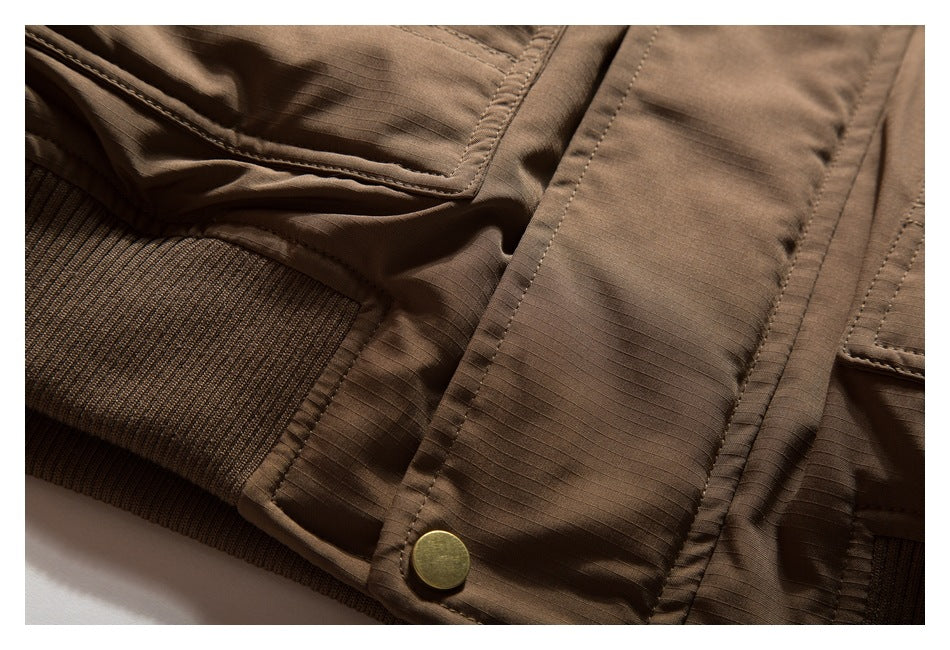 Close-up of a brown garment's stitched panel, brass-tone button, and ribbed knit trim.