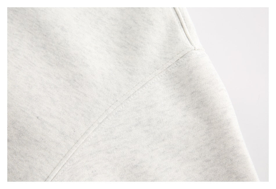 Close-up of a diagonal seam on light heather-gray sweatshirt fabric.