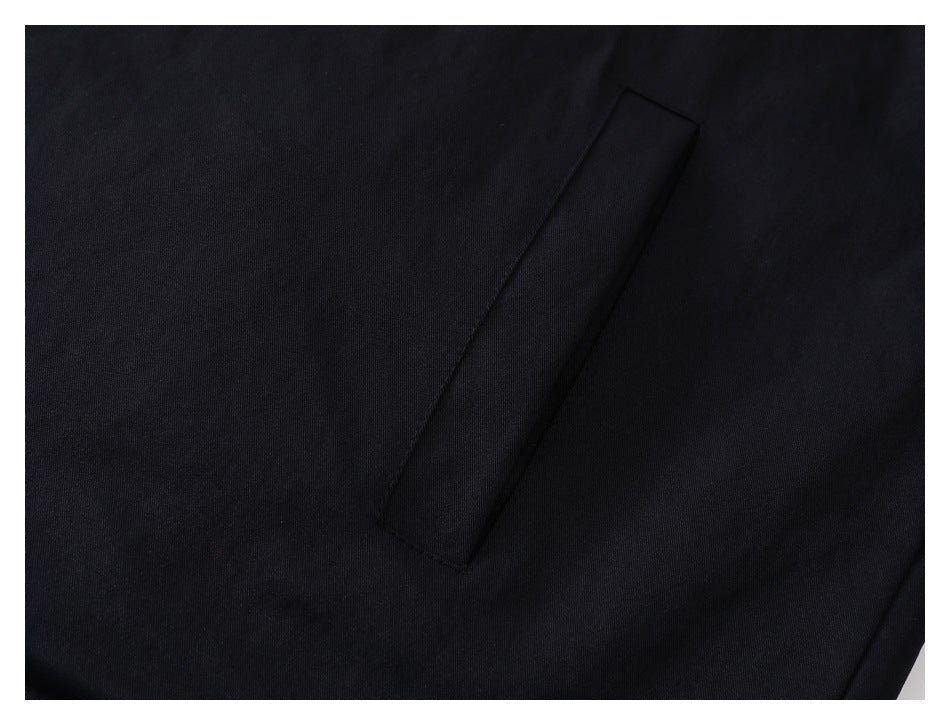 Close-up of a vertical welt pocket on black fabric.