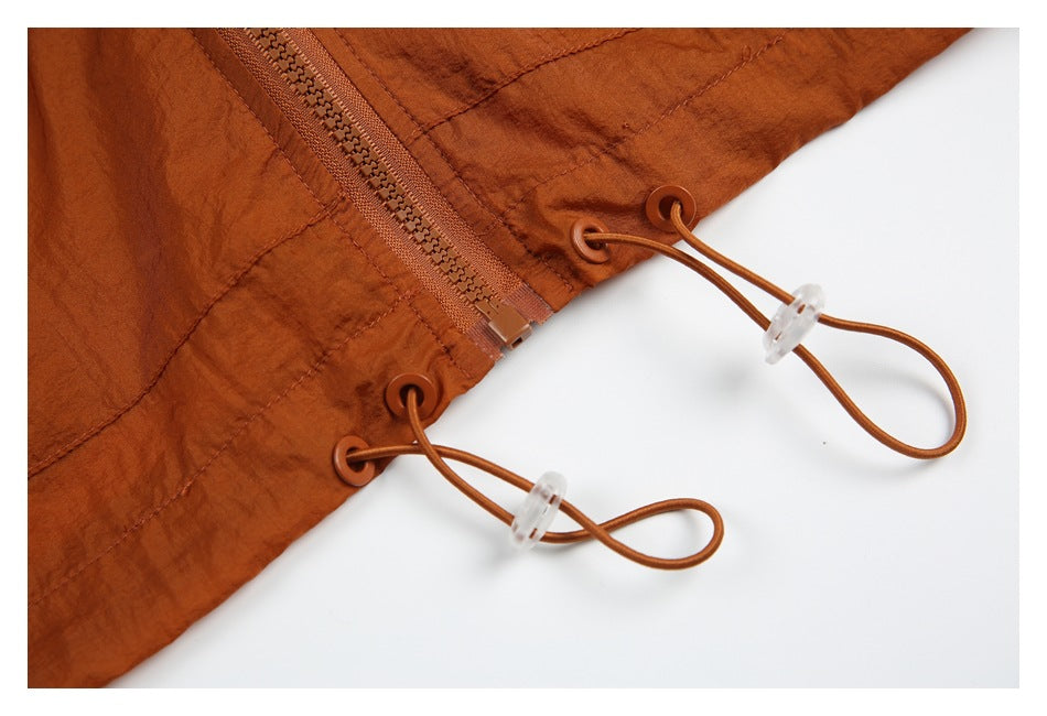 Close-up of the rust jacket hem with a zipper and adjustable drawcords threaded through eyelets.