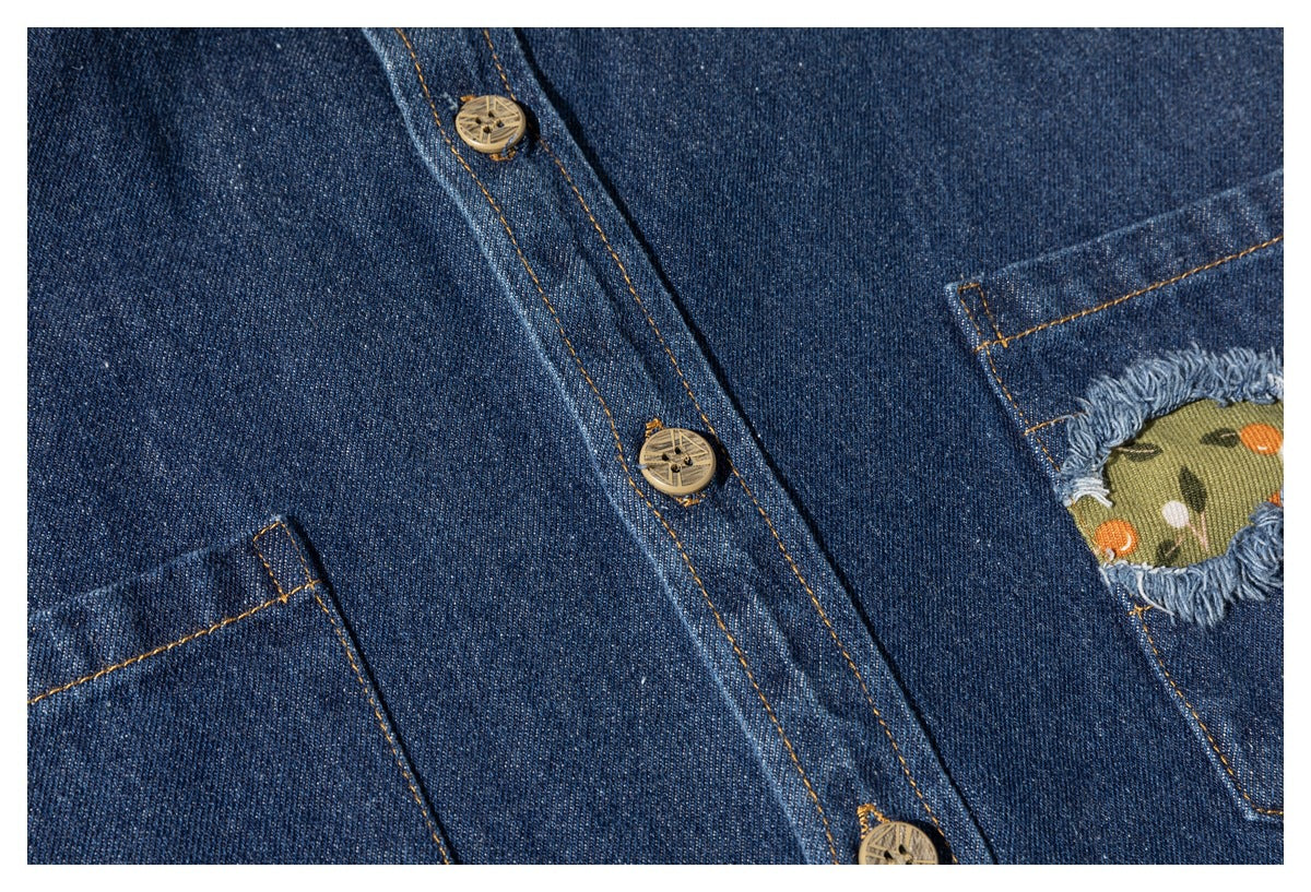 Close-up of a dark blue denim shirt's button placket and pockets, including a frayed pocket opening with floral fabric