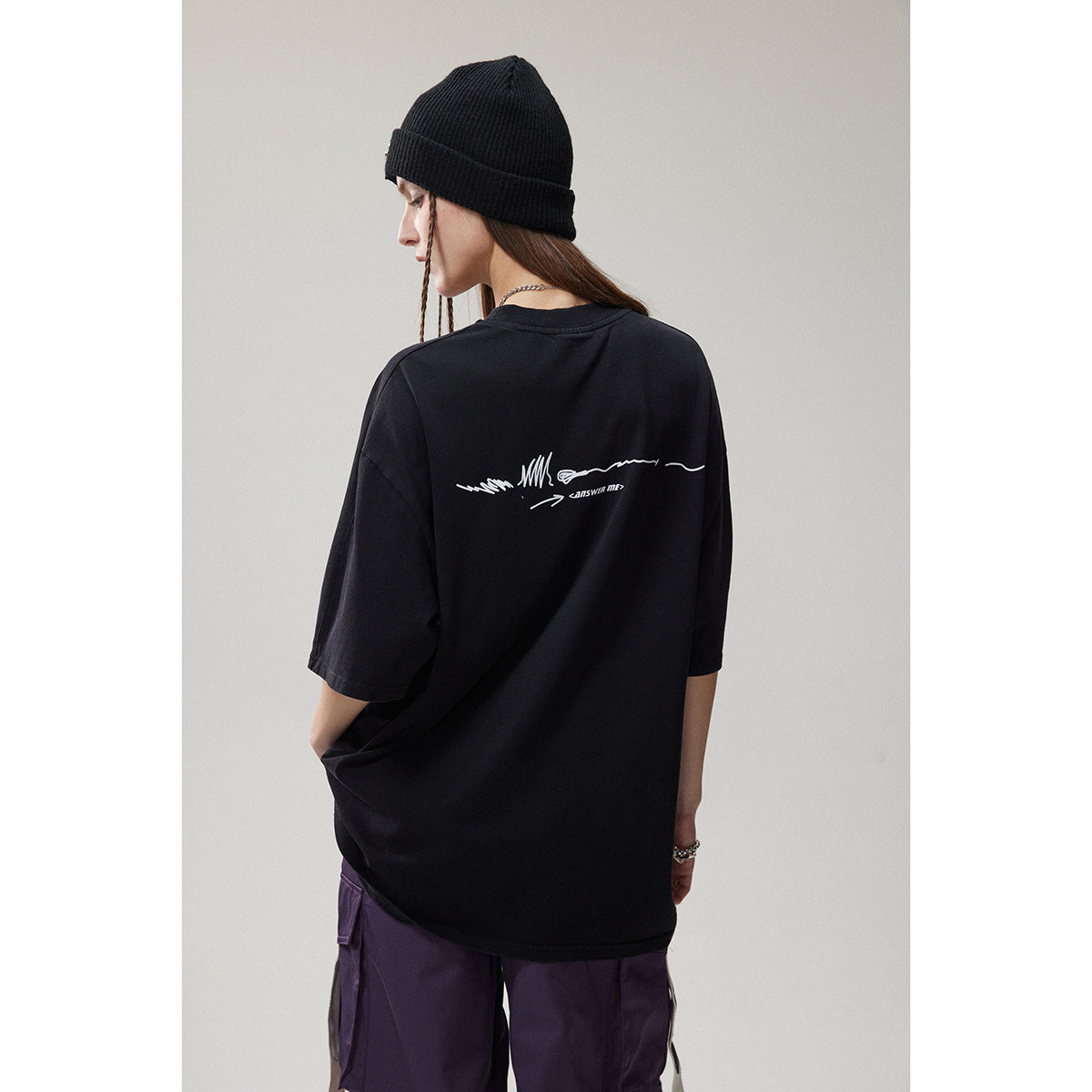 Back view of a model in an oversized black T-shirt with a small white graphic across the upper back.