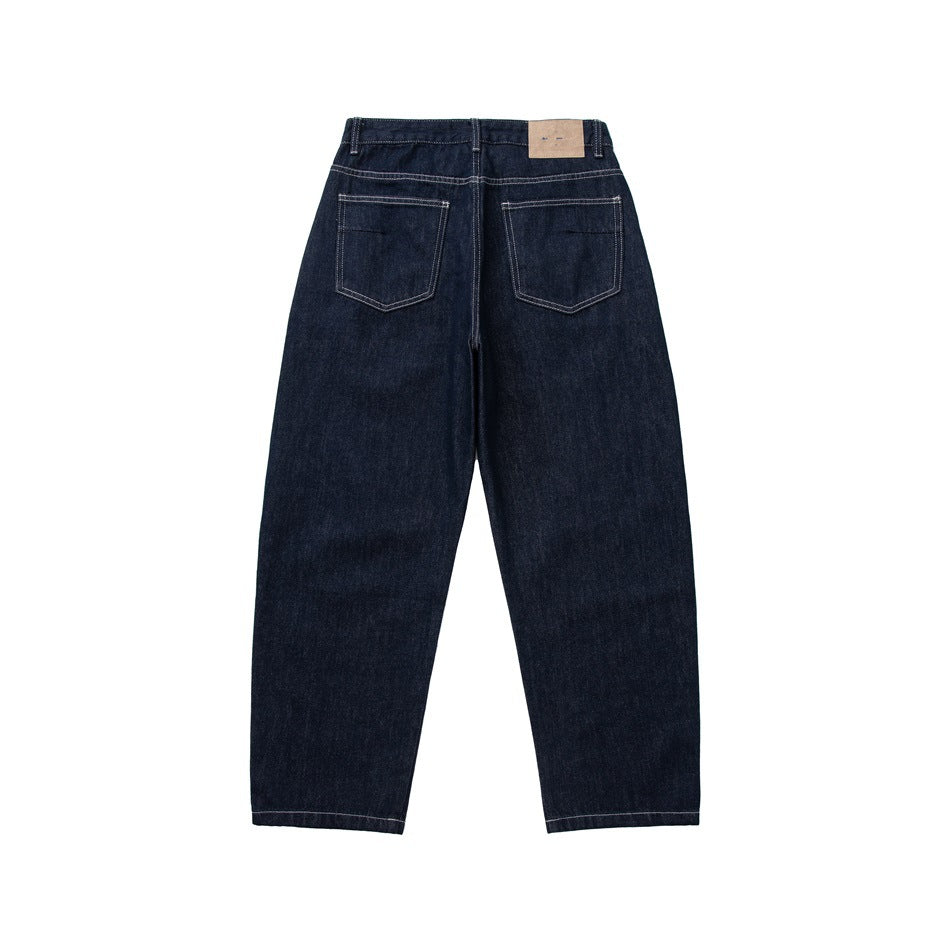 Back view of dark indigo jeans with two patch pockets, contrast stitching and a tan patch at the waistband
