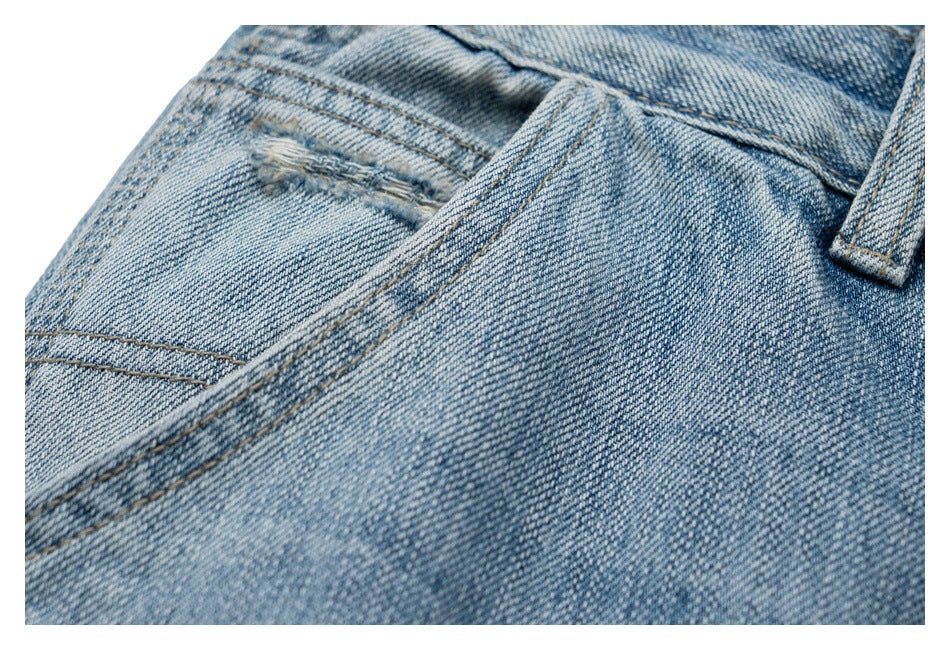 Close-up of light blue denim jeans showing waistband seams, a belt loop, and pocket stitching.