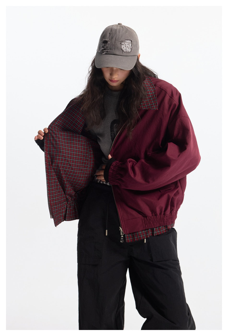 Model opens a burgundy jacket to display its red-and-green plaid lining, collar, and hem trim.