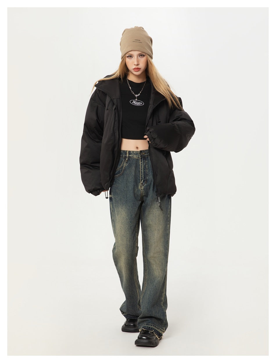 Model standing in an open black puffer jacket with a stand collar, beanie, cropped top and wide-leg jeans