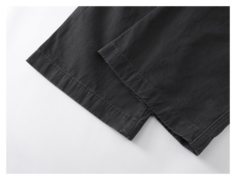 Close-up of the stitched hems on black pant legs.