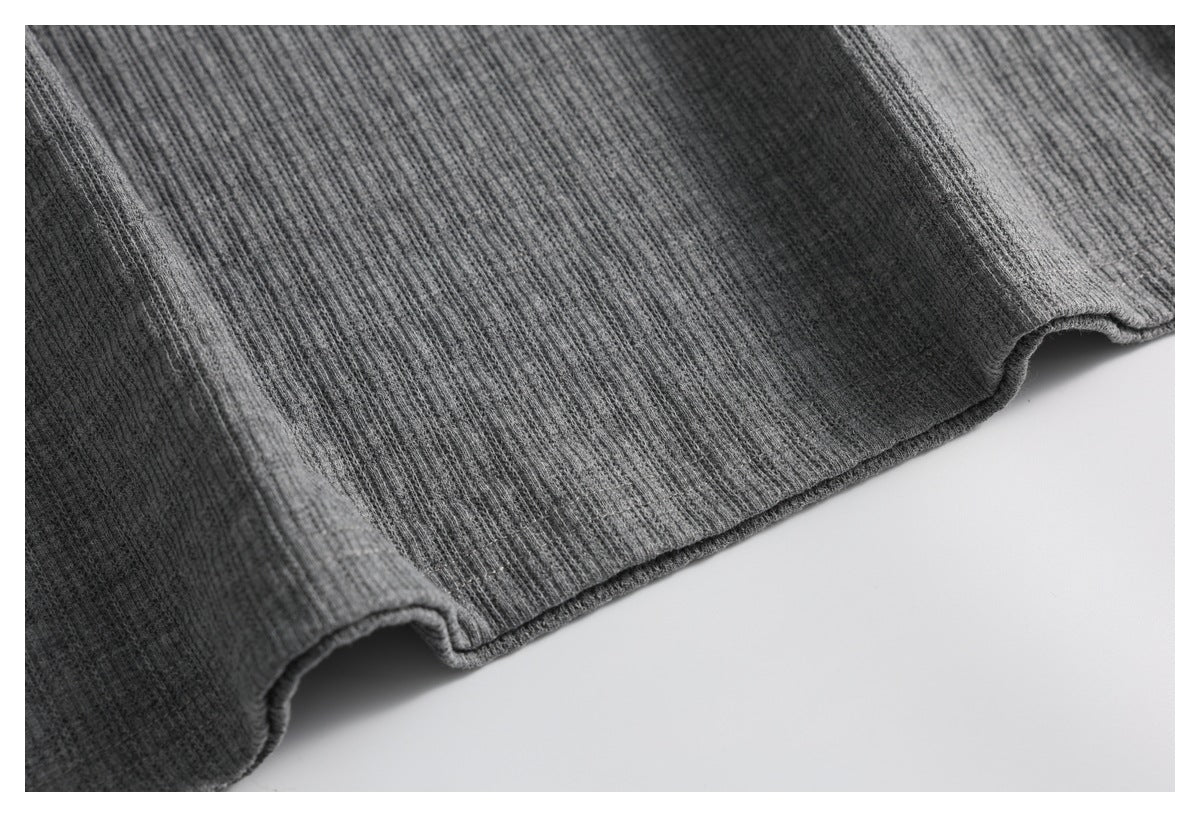 Close-up of the gray ribbed knit garment's curved finished hem.