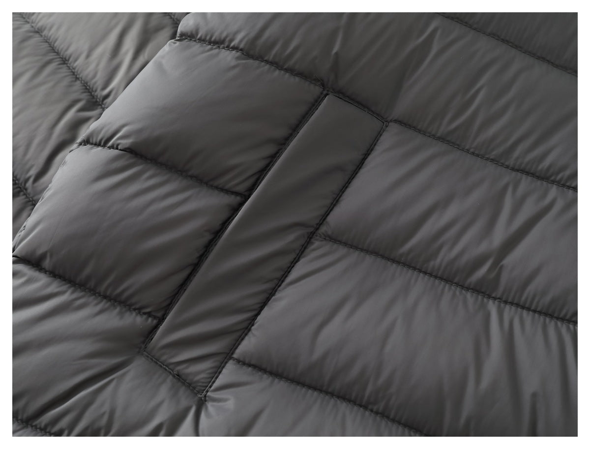 Close-up of a rectangular pocket opening on the charcoal jacket amid horizontal quilting.