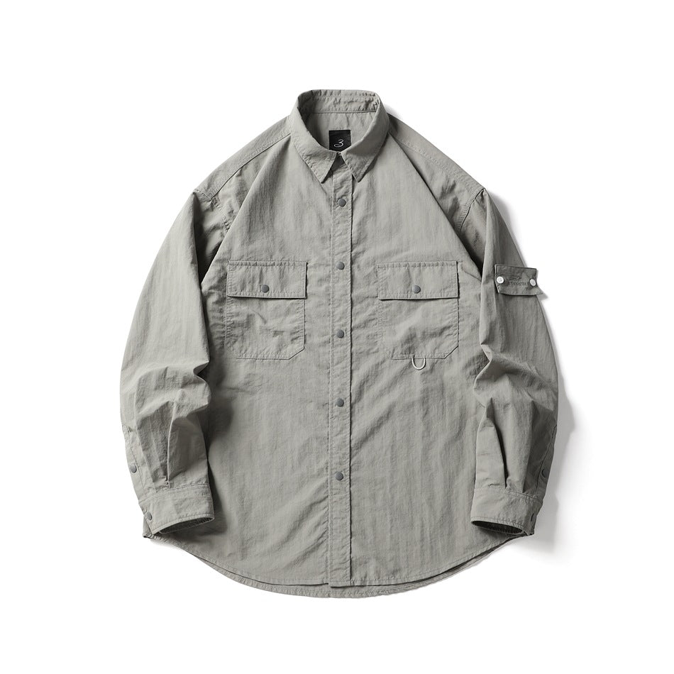 Gray long-sleeve utility shirt with two flap chest pockets, snap placket and sleeve strap, flat lay front view