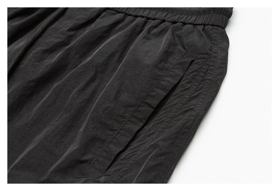 Close-up of a black garment showing a slanted side pocket and wrinkled fabric.