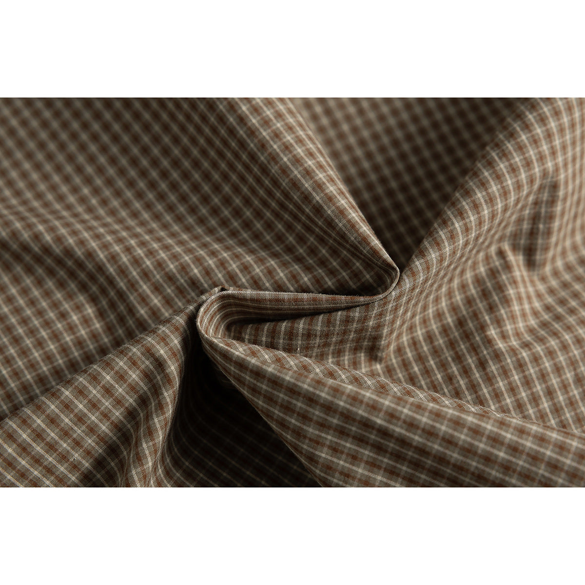 Close-up of brown and beige checked shirt fabric folded to show its pattern and drape.