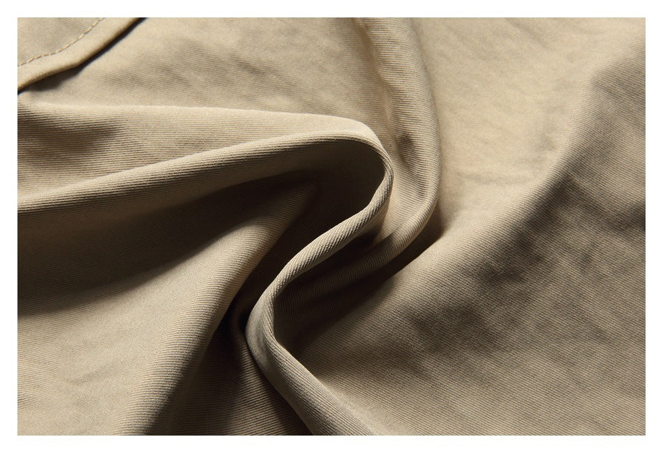 Close-up of beige fabric folded to show its fine diagonal weave and drape.