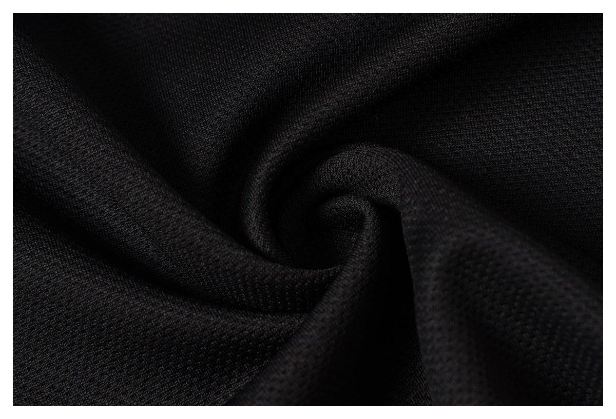 Macro view of the black shirt's textured fabric draped into folds.