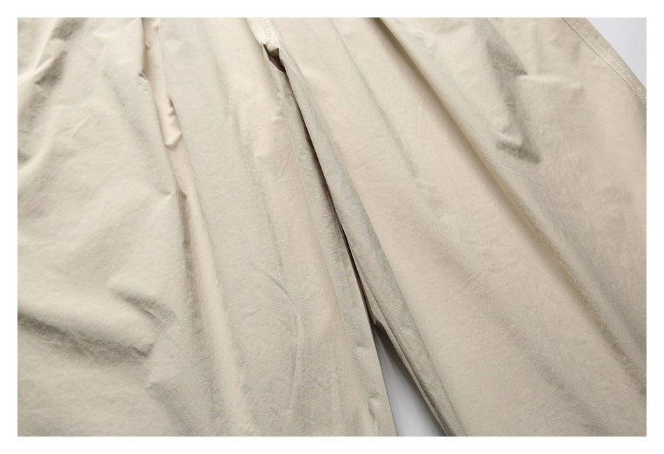Close-up of beige trouser legs showing a long seam and the fabric’s natural folds.