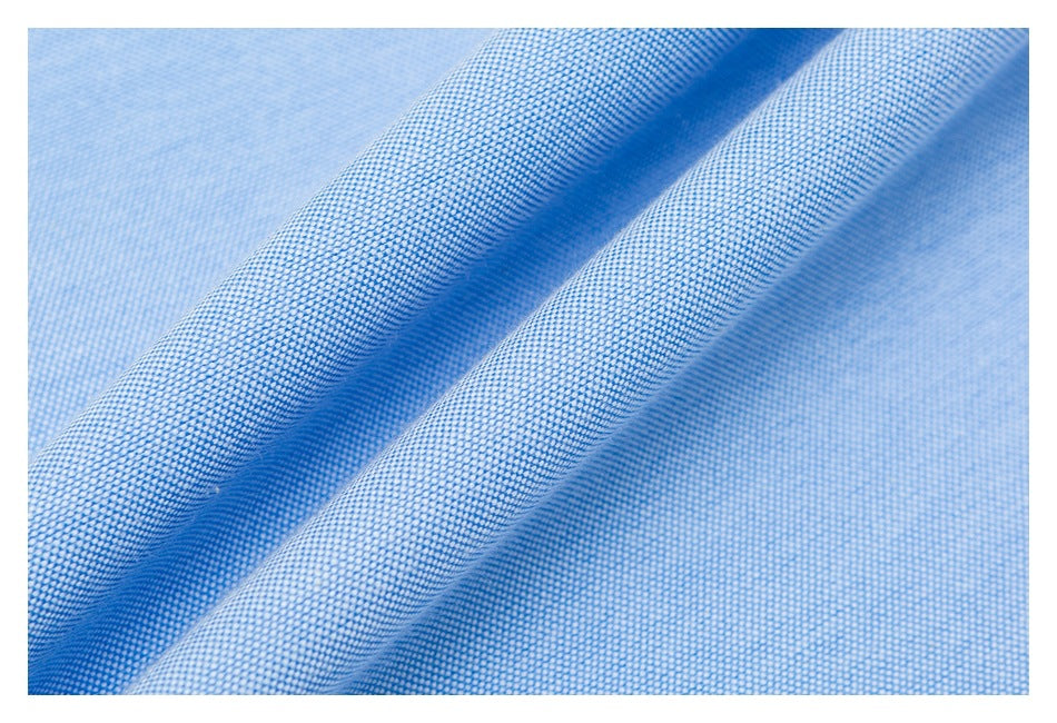 Close-up of light blue woven fabric with a fine, tightly textured pattern and soft folds.