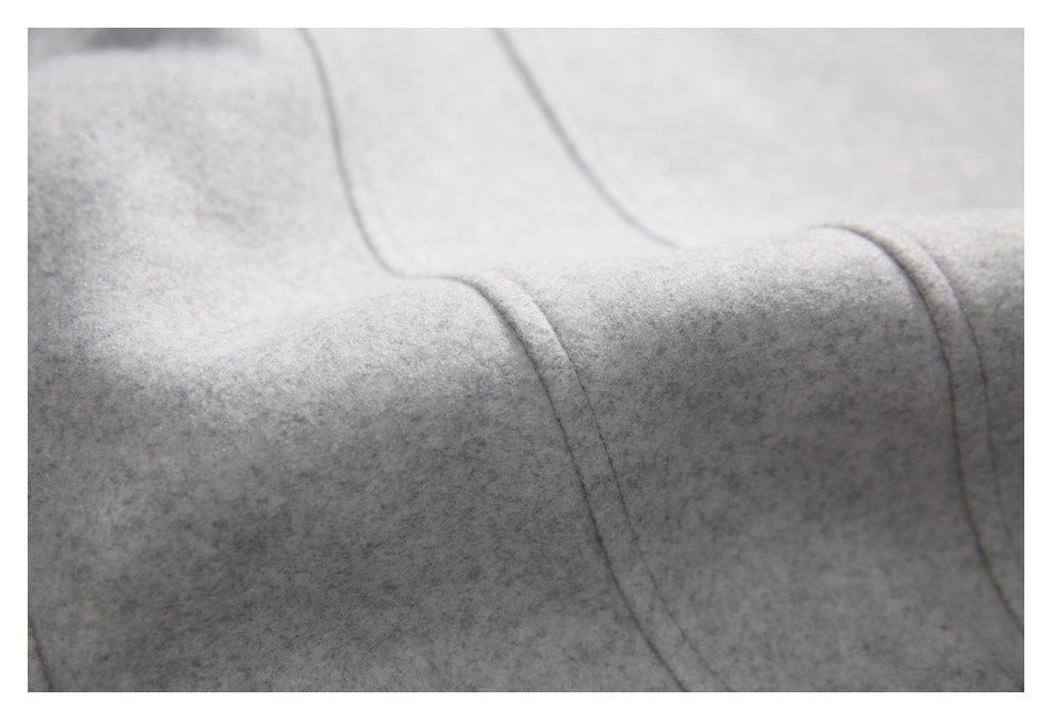 Close-up of light gray fabric with curved stitched seams and panel construction.